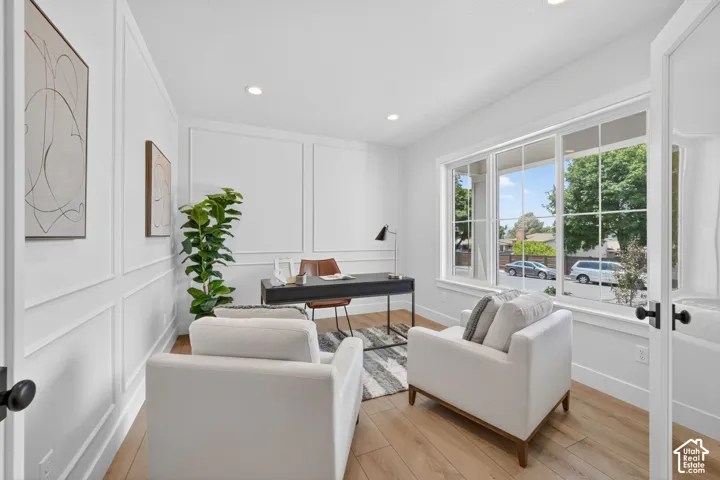 Recessed lighting, wood-finish flooring, accent wall molding, a large multi-pane window, and a paneled entry door