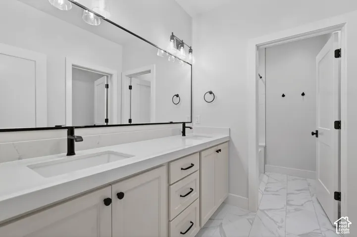 Dual sink vanity with matte black fixtures, quartz countertop, light-toned cabinetry, and decorative hardware