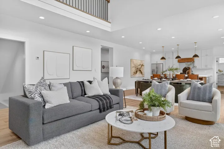 Open-concept living area featuring light wood-finish flooring, recessed lighting, and a white color palette
