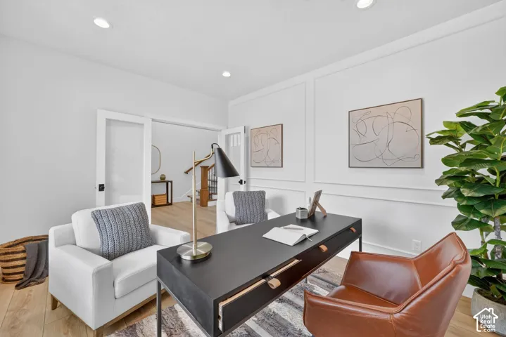Recessed lighting, wood-finish flooring, white wall paneling, and French doors