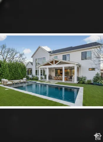 Expansive backyard with a rectangular swimming pool, surrounding patio, and a covered outdoor living area