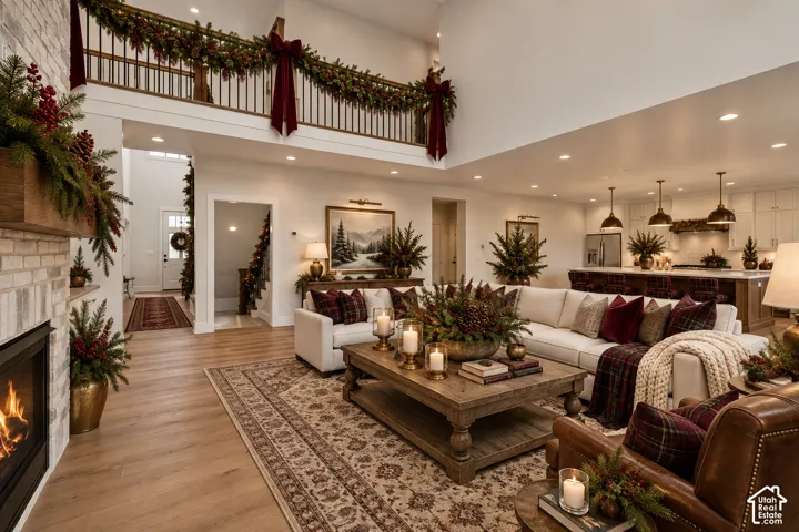Open-concept living space with high ceilings, wood-finish flooring, and a brick-surround fireplace