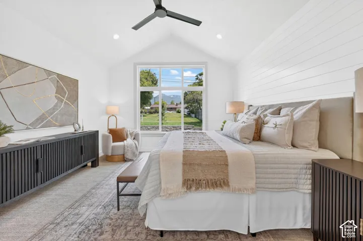 Vaulted ceiling with a flush-mounted ceiling fan, large picture window, and shiplap accent wall