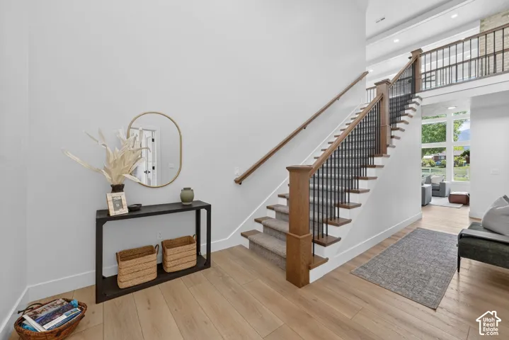 Grand staircase with wood-finish treads and risers, black metal balusters, and a natural wood handrail