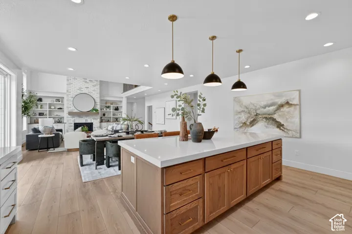 Expansive kitchen island with wood cabinetry and a light-toned countertop, complemented by three pendant lights
