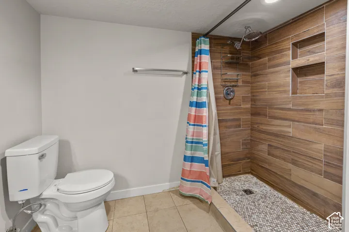 Walk-in shower with wood-finish wall tiling, pebble floor tiling, and dual recessed shelves