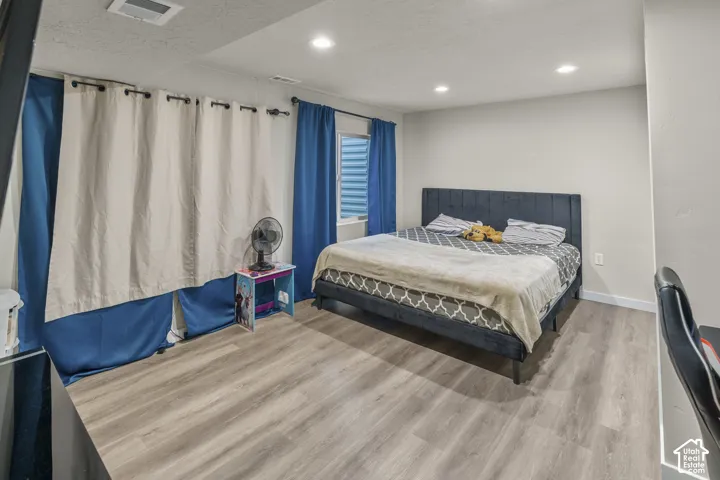 Recessed ceiling lighting, light gray wall paint, wood-finish flooring, and a window with horizontal blinds