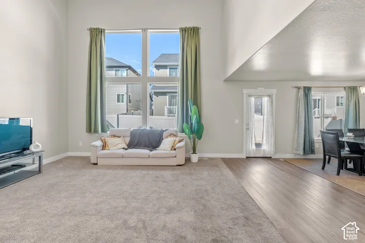Great room with vaulted ceiling, large multi-pane windows, carpet flooring, and wood-finish flooring