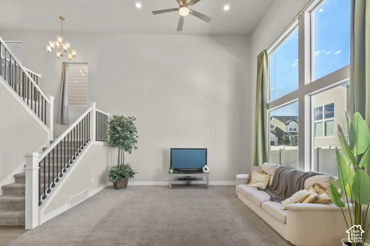 Two-story living area with high ceilings, large windows, recessed lighting, and a ceiling fan
