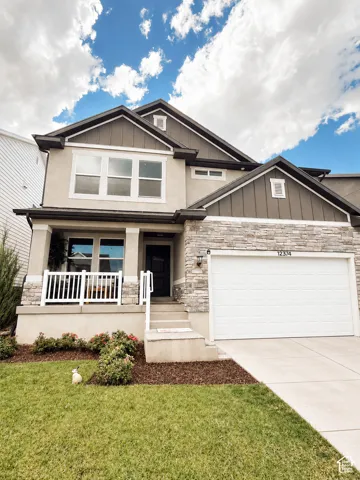 Multi-level exterior featuring stone veneer and vertical siding accents, a covered porch with white railings, a two-car garage, and a concrete driveway