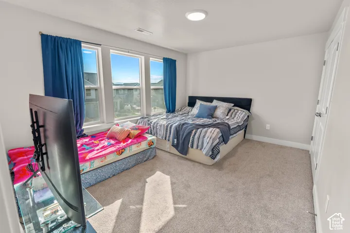 Light grey wall paint with a white trim, featuring three window openings, carpet flooring, a flush-mount ceiling light fixture, and a white panel door