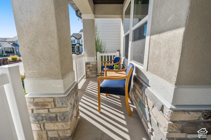 Front porch with textured stucco columns, stone veneer accents, and white railings