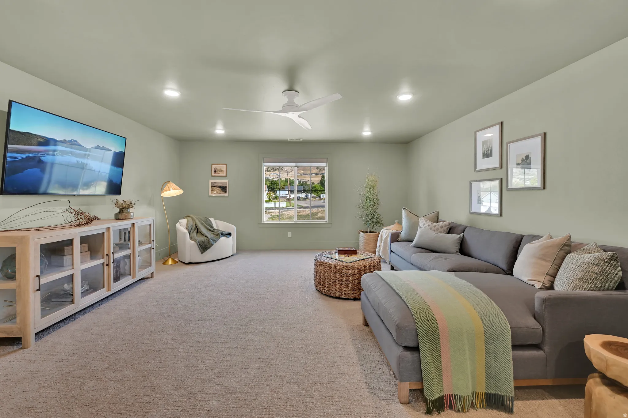 Carpeted living space featuring recessed lighting, a modern ceiling fan, and a large window