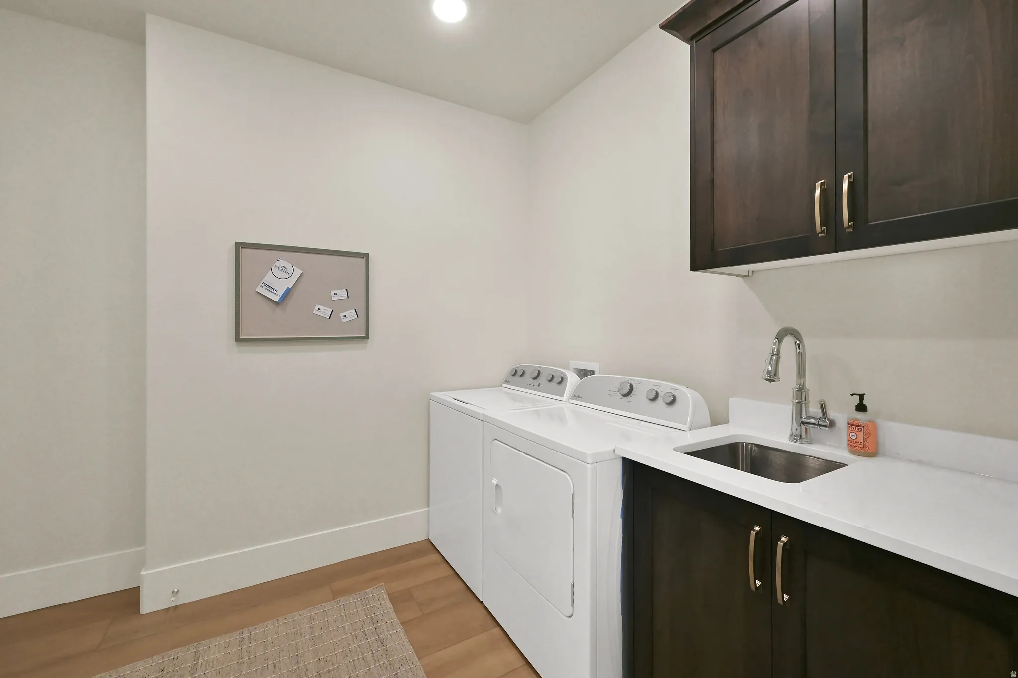 Utility sink with stainless steel faucet, dark wood-finish cabinetry, white countertop, and wood-finish flooring