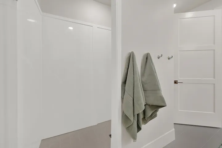 White panel shower enclosure with a tiled floor, adjacent to a three-panel interior door with brushed nickel hardware