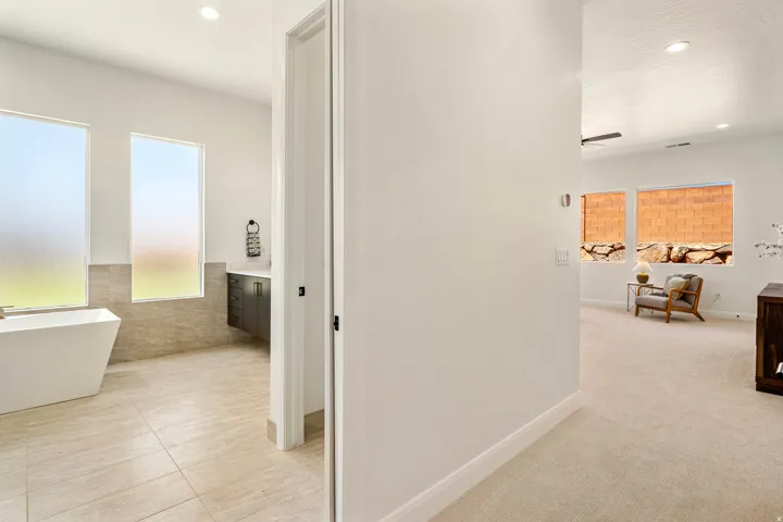 Freestanding tub in a tiled bathroom with frosted windows and a floating vanity