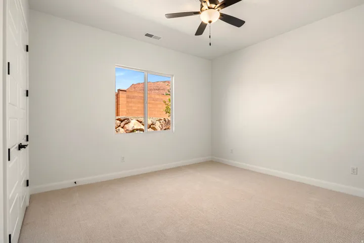 Neutral-toned carpet flooring, white walls, and a ceiling fan with integrated lighting