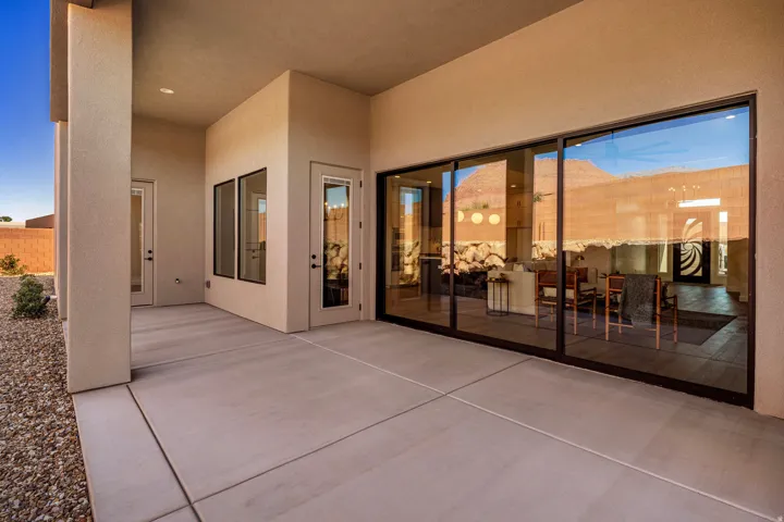 Expansive covered patio with concrete flooring, stucco exterior, and large glass sliding doors