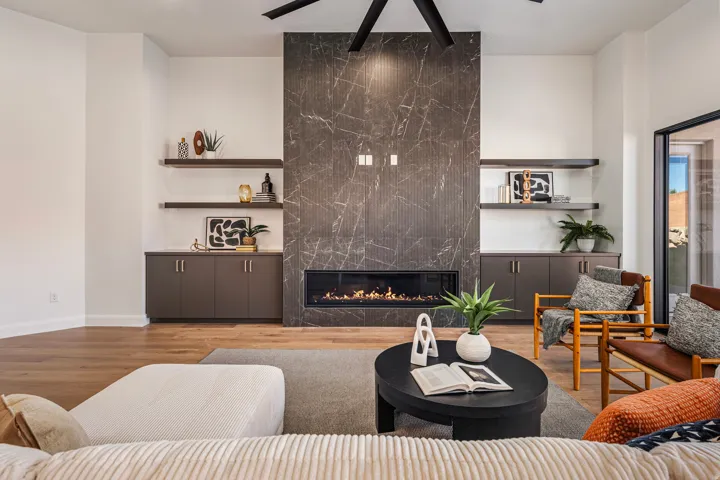 Statement fireplace featuring a linear flame insert and dark marble-look surround, integrated built-in cabinetry, floating shelves, wood-finish flooring, and a large sliding glass door