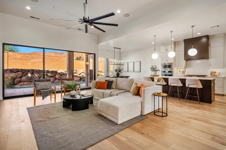 Open-concept living space featuring wood-finish flooring, a contemporary ceiling fan, and a kitchen island with pendant lighting