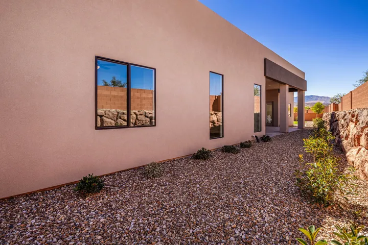Stucco exterior with brown trim windows, gravel landscaping, and a natural stone retaining wall