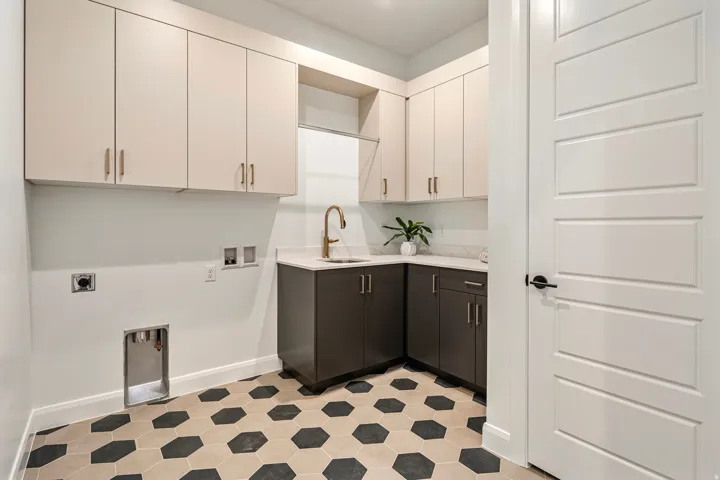 Built-in cabinetry with ample storage, corner sink with a gold-finish faucet, hexagonal floor tiling, and a white paneled door
