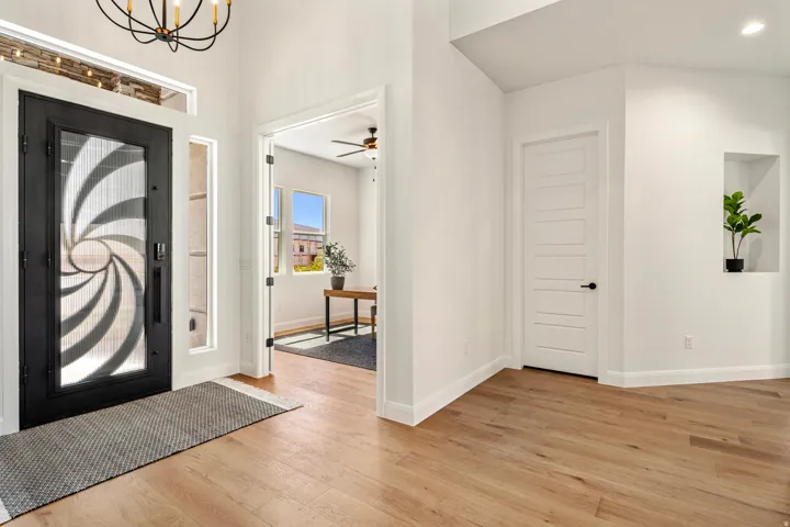 Entryway with wood-finish flooring, a decorative glass entry door, high ceilings, and an integrated wall niche