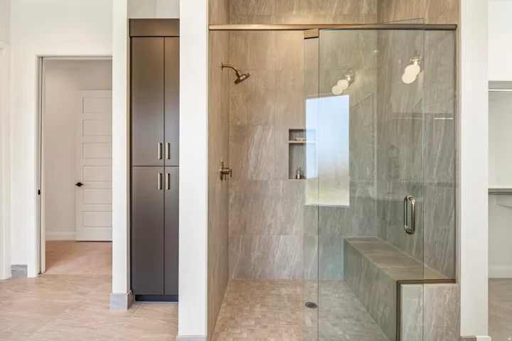 Glass-enclosed shower with a built-in bench, tiled walls, and a recessed niche