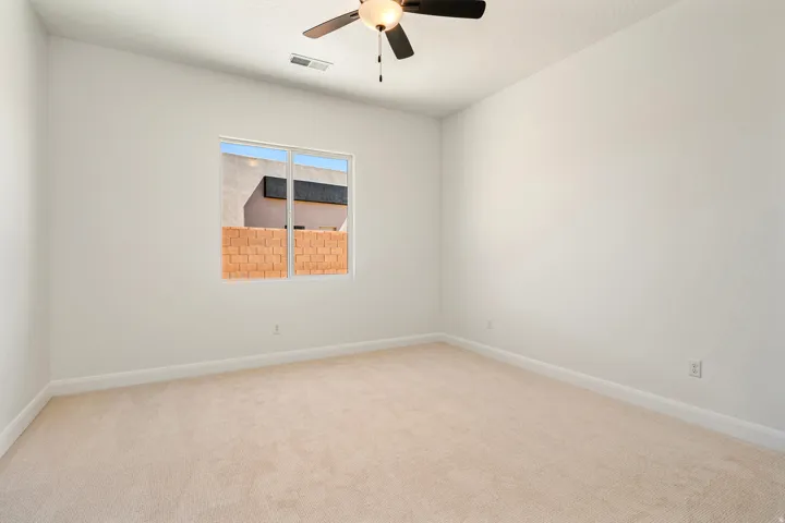 Neutral-toned carpeting, white painted walls, and a ceiling-mounted fan with integrated lighting