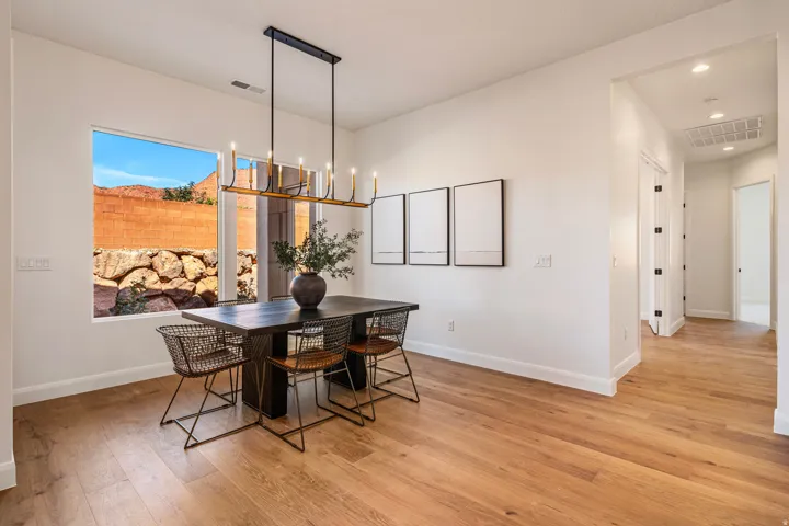 Open concept dining area featuring wood-finish flooring, a linear chandelier, and a large window