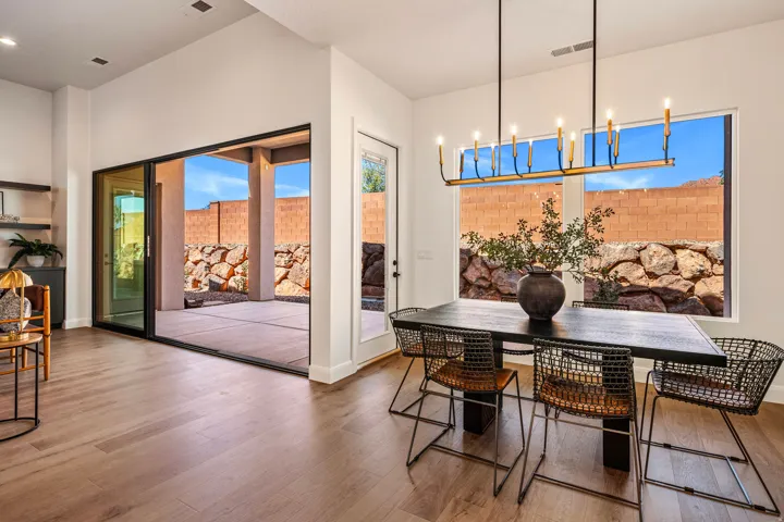 Expansive sliding glass doors, wood-finish flooring, recessed lighting, and a modern linear chandelier