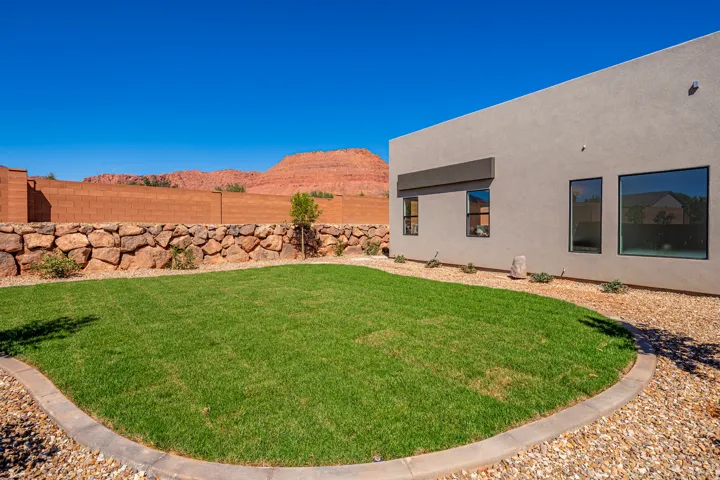 Manicured lawn with a curved concrete border, surrounded by gravel landscaping