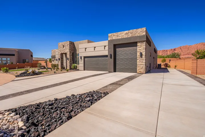 Modern exterior featuring stacked stone accents, two garage doors, and integrated lighting