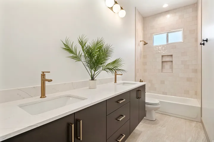 Dual vanity with integrated sinks, white quartz-finish countertop, and bronze-finish fixtures