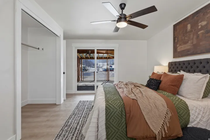 Sliding glass door access to a covered patio, neutral wood-finish flooring, a contemporary ceiling fan, and a built-in closet with a hanging rod