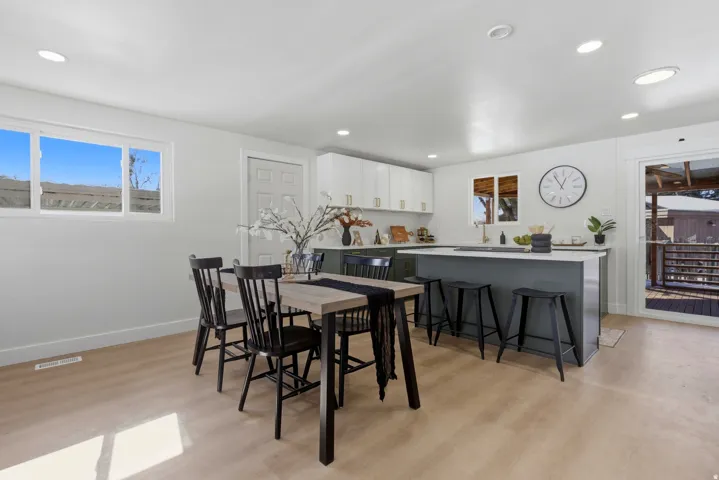 Open-concept living space with light wood-finish flooring, recessed lighting, and a white interior door