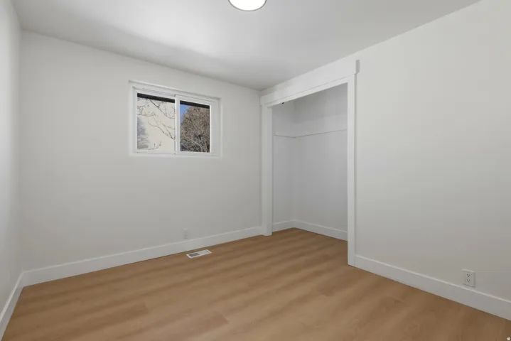 White walls, wood-finish flooring, recessed lighting, white trim, and a built-in closet