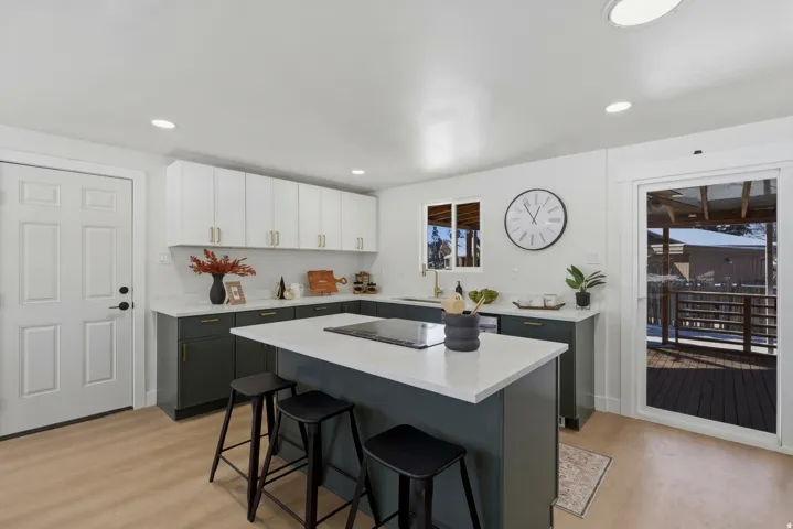 Modern kitchen featuring two-tone cabinetry, light-toned wood-finish flooring, recessed lighting, and a kitchen island with seating