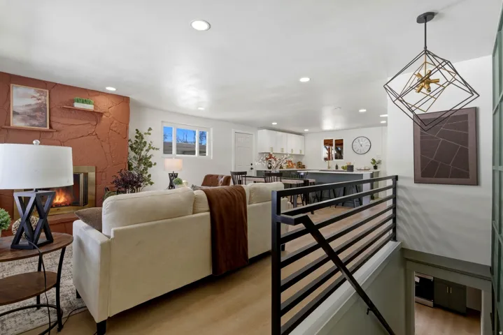 Recessed lighting, wood-finish flooring, and a stone-clad fireplace with a brass-finish insert