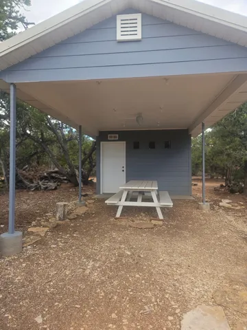 Covered carport with a light blue exterior, featuring a white access door