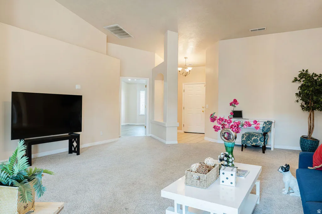 Spacious living area featuring neutral carpeting, vaulted ceilings, and an arched entry