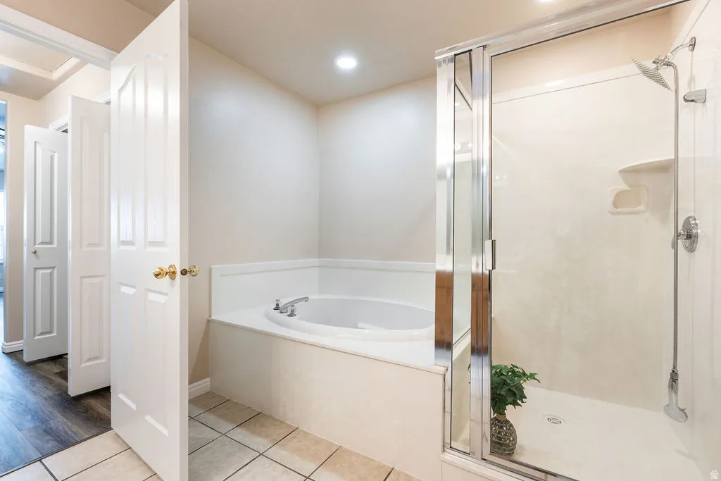 Enclosed shower with glass door, separate built-in soaking tub, and recessed lighting
