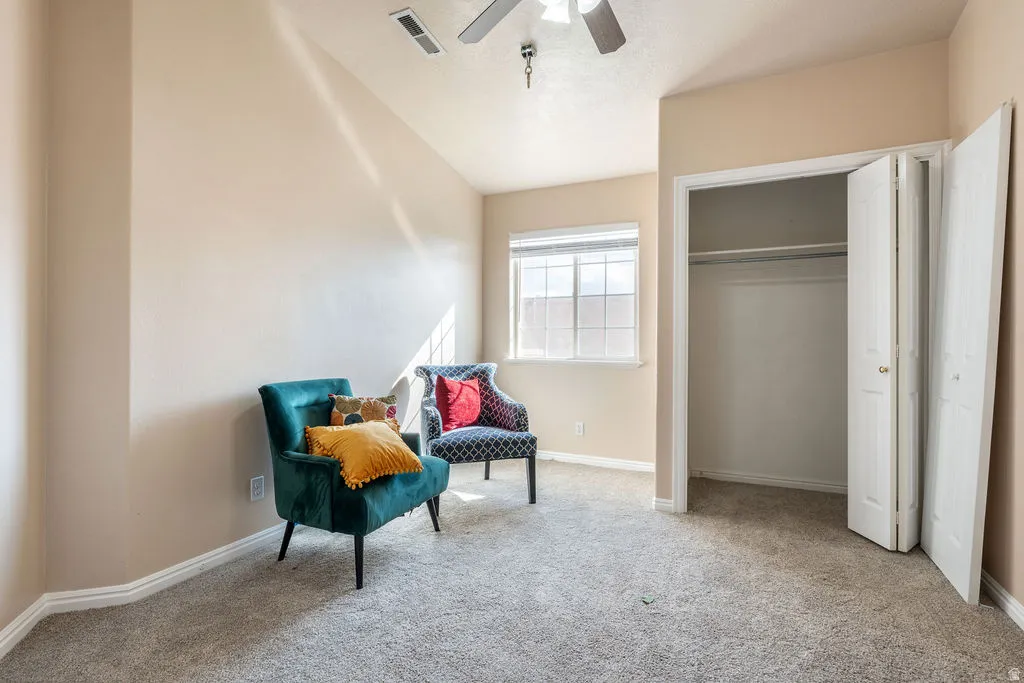 Vaulted ceiling, carpet flooring, window with grid panes, ceiling fan, and bi-fold closet doors