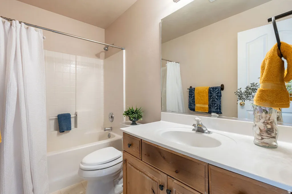 Bathroom featuring a white bathtub, ceramic tile surround, integrated vanity sink, wood-finish cabinetry, and a large wall-mounted mirror
