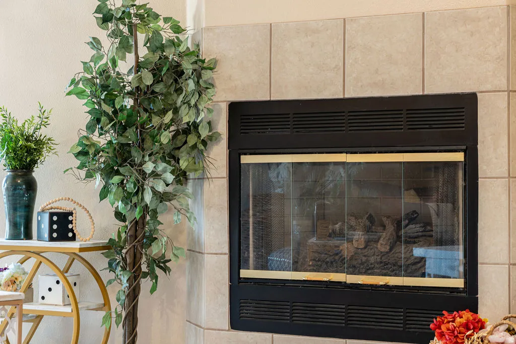 Fireplace with a black metal frame and glass doors, surrounded by light-toned tile