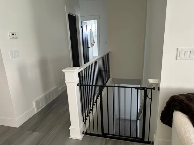 Wood-finish flooring, white walls, and a contemporary black metal and white wood railing system