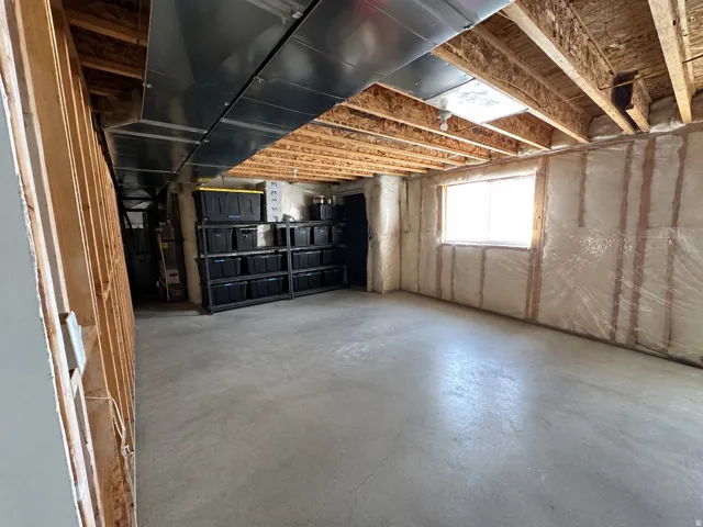 Unfinished basement with exposed ceiling joists, concrete flooring, and a single window