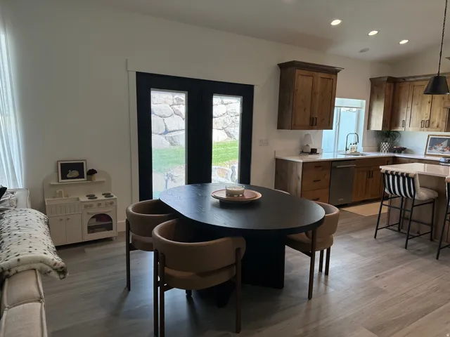 Wood-finish flooring, dark-framed double doors, light wood cabinetry, light-toned countertops, recessed ceiling lighting