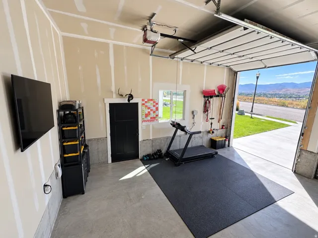 Finished garage space with concrete flooring, a black three-panel door, and an overhead garage door