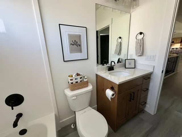 Bathroom featuring a wood-finish vanity with an integrated sink, light-colored countertop, and a large wall-mounted mirror